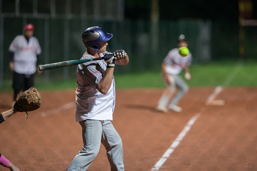 Baseball pitcher, ball sports and a athlete woman ready to throw and pitch during a competitive game or match on a court. Fitness, workout and exercise with a female player training outside on field