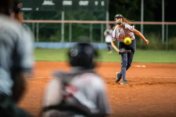 Female Softball Pitcher Looking at the Ball Mid Air