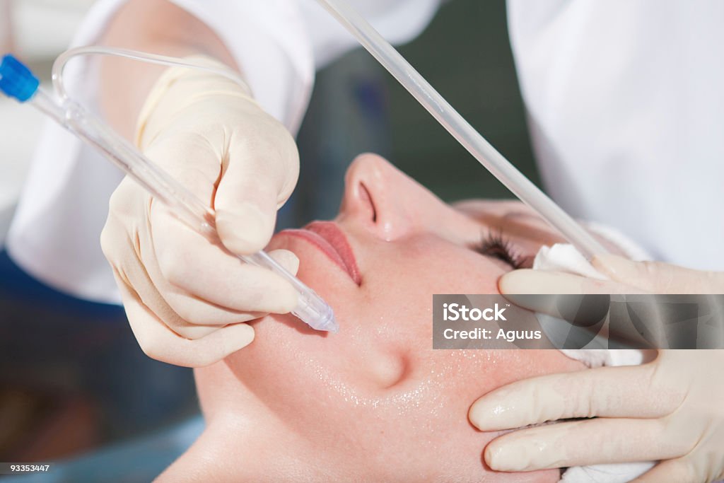 Woman having jet peeling facial treatment Closeup shot of woman having jet peeling facial treatment in clinic in beauty saloon (focused on the penetrated face area). Human Face Stock Photo