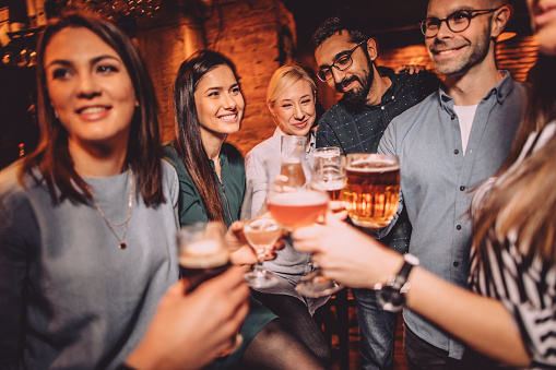 Smiling friends in a pub, toasting to their friendship