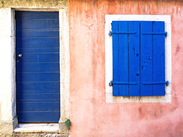 old pink painted building with blue door and blue window shutters.