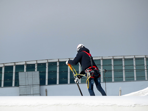 Worker removes the snow on the roof