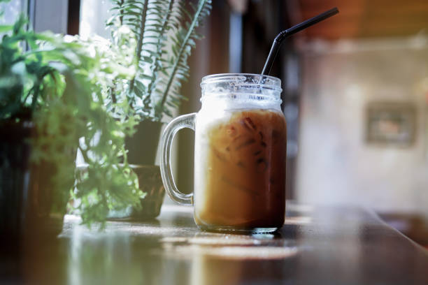 istock Summer refreshing drinks, cold iced coffee on wood table in relaxing atmosphere coffee shop with blurred indoor potted plants near window. 933599012