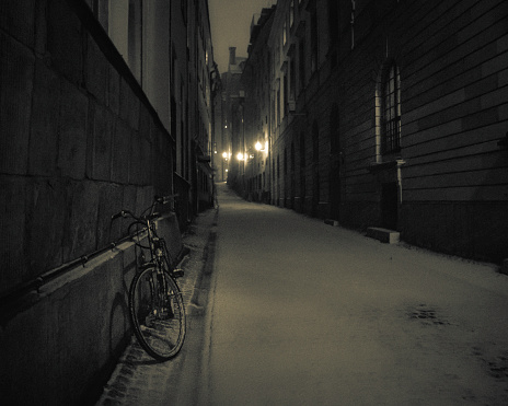 a lone bike in a snowy and dark alley