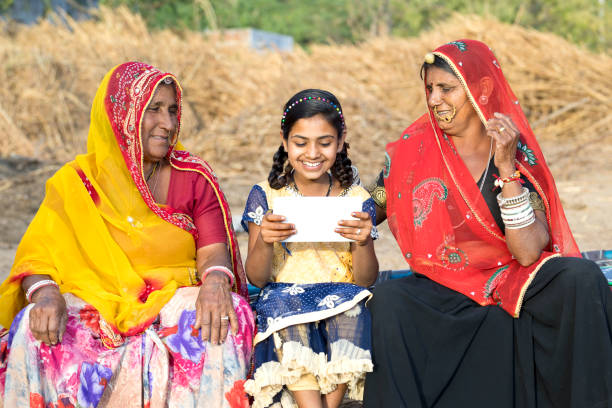 Rural women with girl using digital tablet Rural Indian women with little girl using digital tablet bed of hay stock pictures, royalty-free photos & images