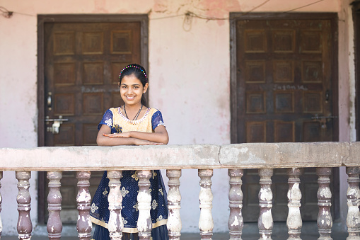 Portrait of happy Indian girl standing in balcony of old house