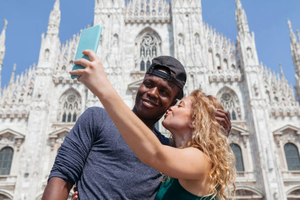 jeune couple amoureux prenant un selfie devant la cathédrale de milan, en été, italie - couple black american culture kissing photos et images de collection