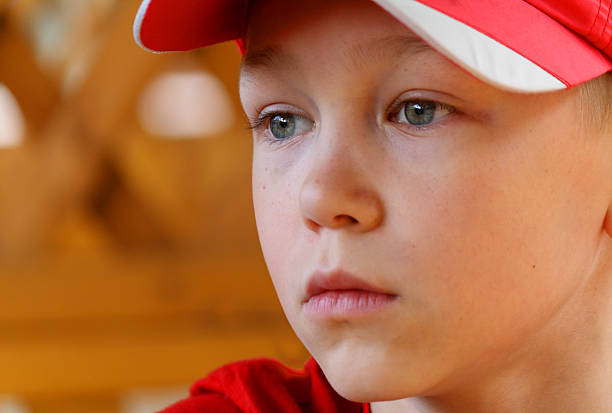 Pensive young man with a backwards baseball cap looking thoughtfully upwards with his hand on his chin