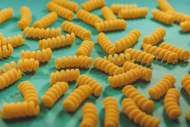 Top view of fusilli pasta on the bright blue green background. Fashion food
