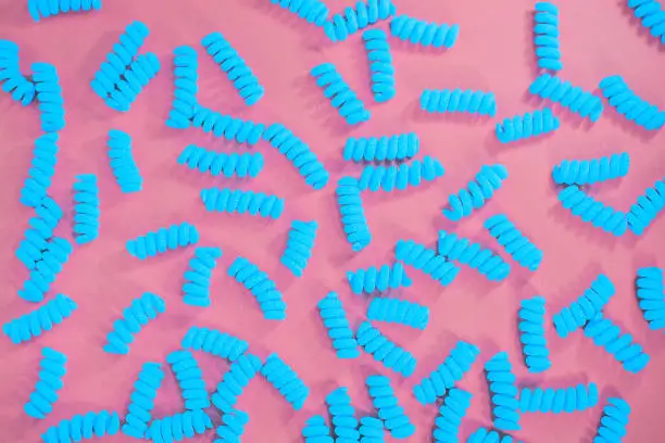 Top view of blue fusilli pasta on the bright pink background. Fashion food. Abstract