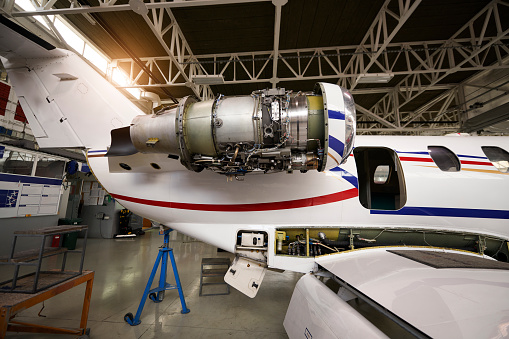 Private jet airplane inside the hangar opened for regular maintenance and repair service.
