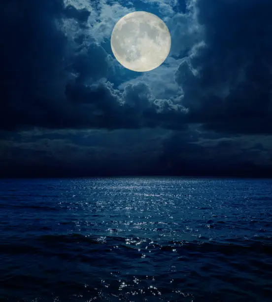 Photo of super moon in dark clouds over sea