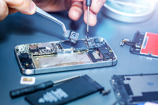 Technician repairs the damaged mobile phone. Serviceman is repairing a damaged cell phone. Technician repairs the damaged smartphone. serviceman repairs the damaged camera on the smartphone.