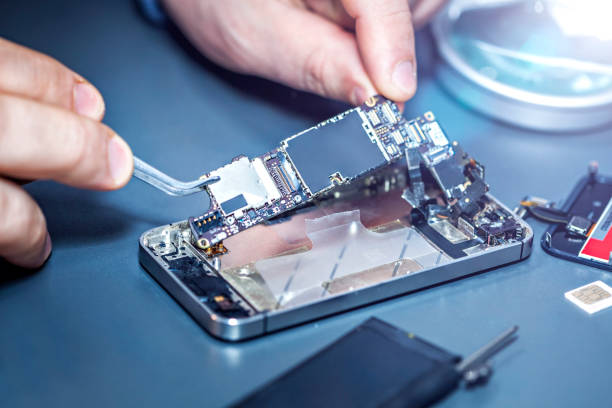 serviceman is repairing a damaged mobile phone. - service electronics industry circuit board capacitor imagens e fotografias de stock