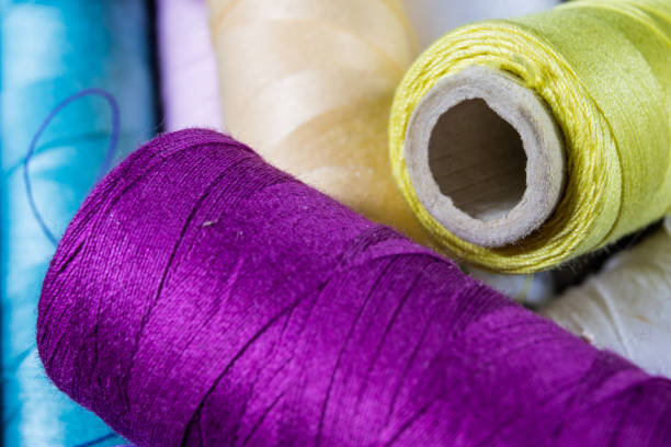 Threads and needle on the table in a tailor's workshop. Close-up sewing accessories. Dark background.