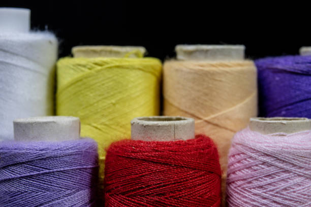 istock Threads and needle on the table in a tailor's workshop. Close-up sewing accessories. Dark background. 933641426