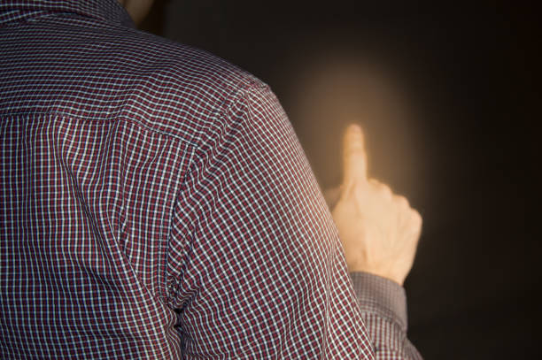 Index finger raised up, man shows gesture of attention, touch, point out, back view.