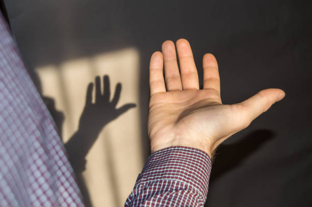 istock The young man holds an empty hand with his palm up, a shadow on the wall 933652572