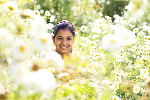 Happy Indian girl in field of daisy flowers