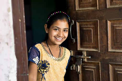 Happy Indian girl opening front door of house