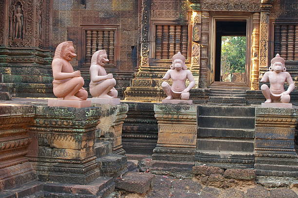 Stone monkey statues in front of a richly decorated ancient temple entrance, part of a Khmer temple complex in Southeast Asia.