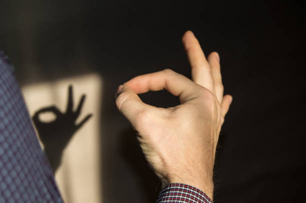 man gesturing OK sign on the wall the shadow of a hand.