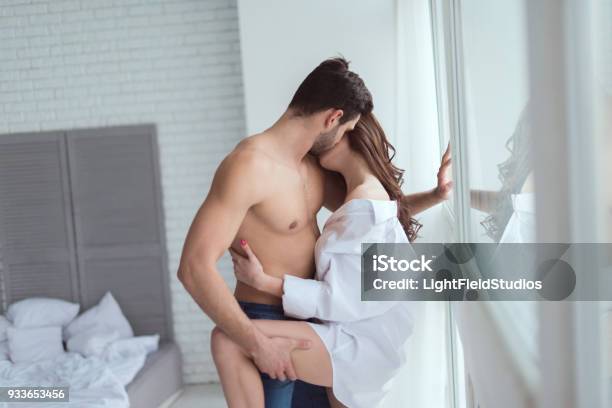 Side View Of Young Sexy Couple Standing At Window At Home Stock Photo - Download Image Now