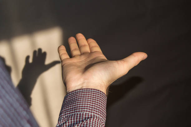 istock The young man holds an empty hand with his palm up, a shadow on the wall 933653990