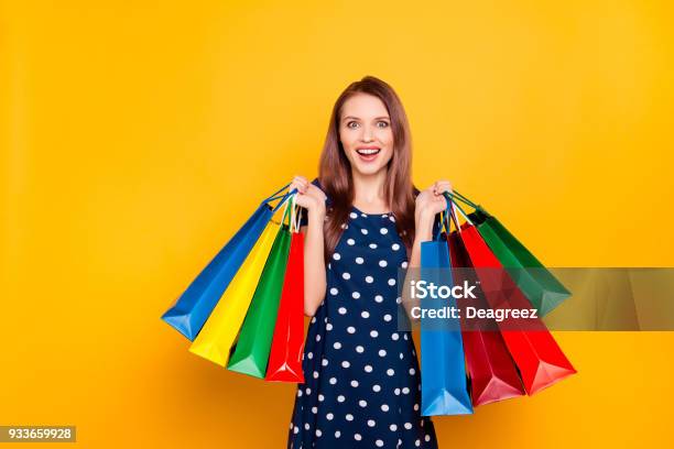 Foto de Retrato De Menina Feliz Encantador Bonito Louca Feliz Animado Que Comprou Um Monte De Roupas A Preços Baixos Segurando Os Pacotes Em Duas Mãos Levantadas Isolado Em Fundo Amarelo Inacreditável Compras e mais fotos de stock de Comércio - Consumismo