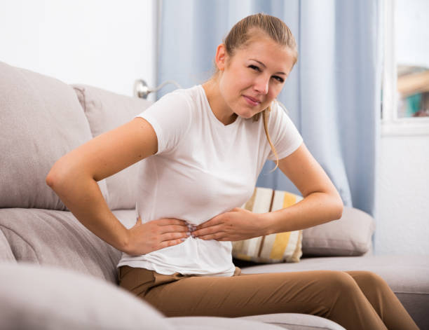 istock Female is having stomach ache and she sitting unhappy 933661844