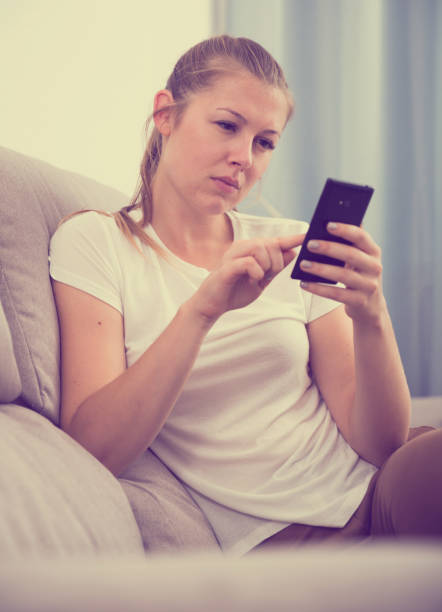 istock Young female is chatting phone and boreding alone 933661854