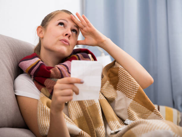 istock Sick woman lying with plaid and reading recipe 933661862