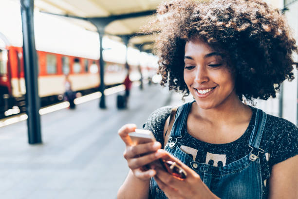 istock Smiling woman using smart phone on station 933665360
