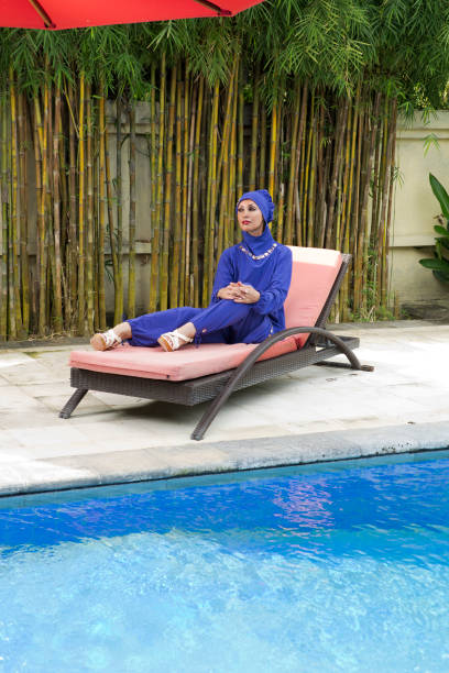 迷人的婦女在穆斯林泳裝 burkini 在泳池附近的沙灘木板床上 - 回教泳裝 圖片 個照片及圖片檔