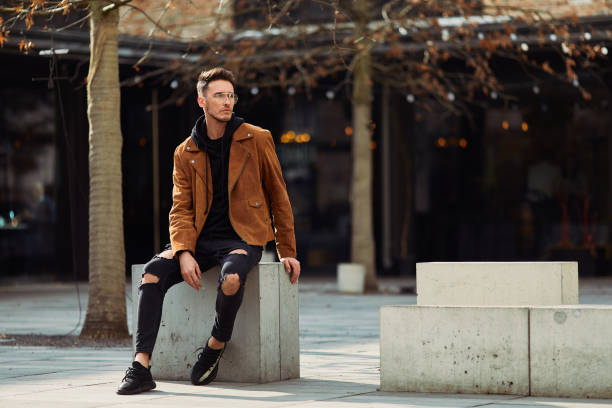 istock Model looking man sit on the bench in modern park background, look on his watch and around 933670218