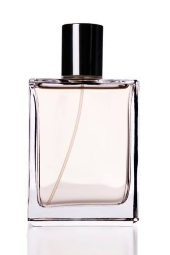 Glass perfume bottle on white podium. Floral arrangement. Minimal mockup style, soft focus, low angle.