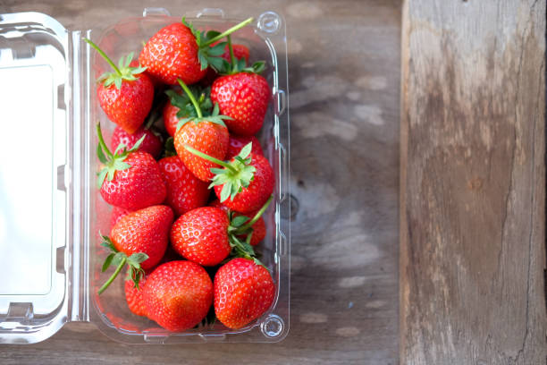 istock Strawberry in the plastic box on wood table 933670950
