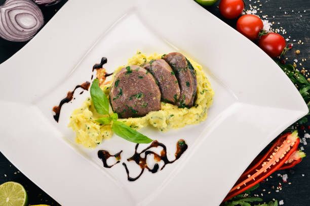 istock Boiled veal tongue with mashed potatoes on a plate. On a wooden background. Top view. Copy space. 933671104