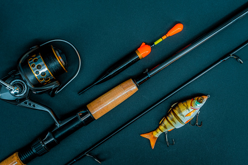 Fishing tackle still life on a wooden background. The rod and wobblers is located diagonally.