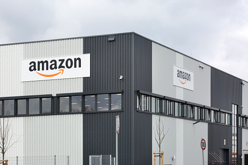 Facade and logo of new logistics center of amazon in Raunheim-Moenchhof, Germany. Amazon (Amazon.com, Inc.) is an American electronic commerce and cloud computing company and the largest Internet retailer in the world as measured by revenue and market capitalization.