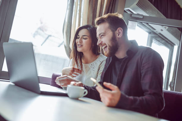 istock Smiling Couple Drinking Coffee and Watching Funny Videos on Laptop 933804190