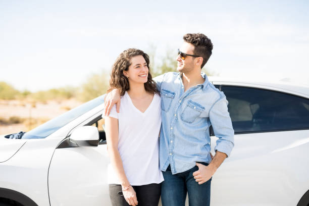 istock Happy young couple standing by a car 933804468