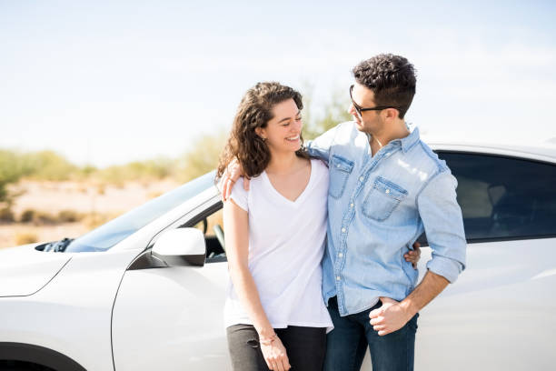 istock Happy young couple outdoors by their car 933804620