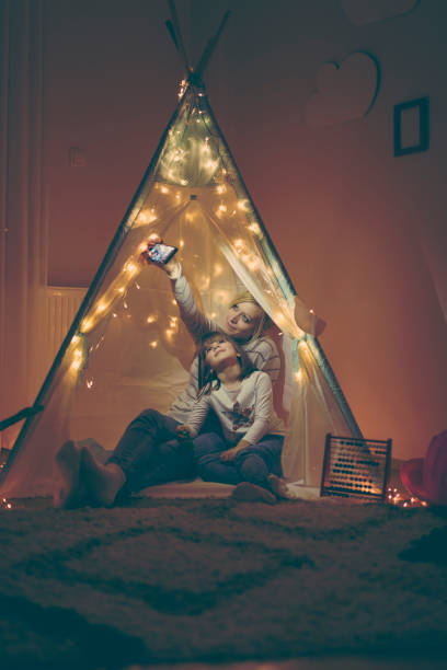 istock Mother and daughter taking selfie in a teepee 933826912