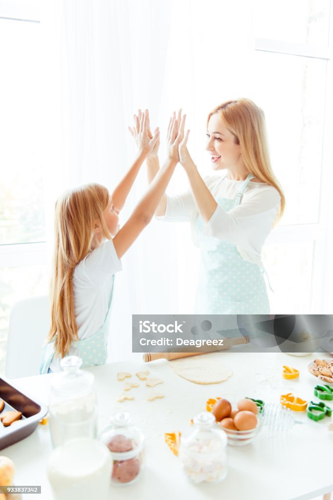 Maternity parenthood white light win winner tasty finished complete concept. Vertical side view photo of cheerful excited cute lovely sweet charming mommy small kid giving high-five in light kitchen Cooking Stock Photo