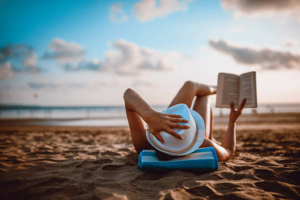 lecture féminine et le coucher du soleil sur la plage de l’océan - life back lit people happiness photos et images de collection