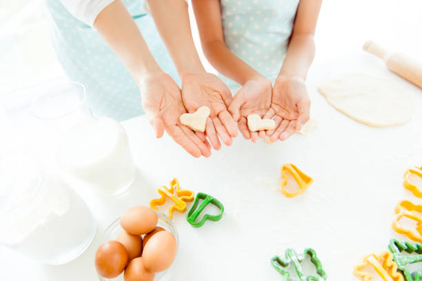 Learn upbringing friends support 14 february valentine hobby courses rolling-pin relatives sisters two concept. Cropped top view close up photo of hands holding showing small hearts made of raw dough