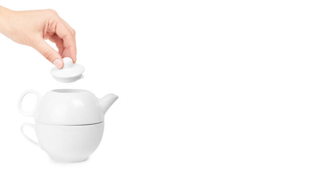 istock white ceramic kettle or teapot with cup in hand. Isolated on white background. copy space, template 933856352