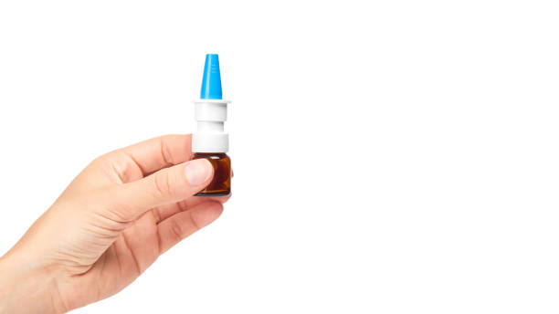 istock female hand holding nose spray bottle. Isolated on white background. copy space, template 933856374