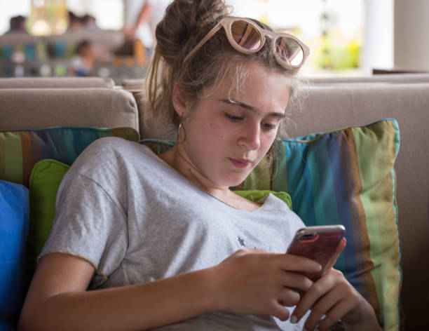 istock Adolescent girl watching message on mobile phone 933860422